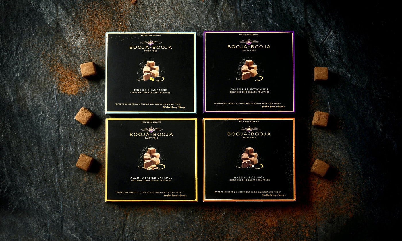 The Booja-Booja twelve truffle pack collection of vegan and organic chocolate truffles, photographed on a slate background with individual chocolate truffles