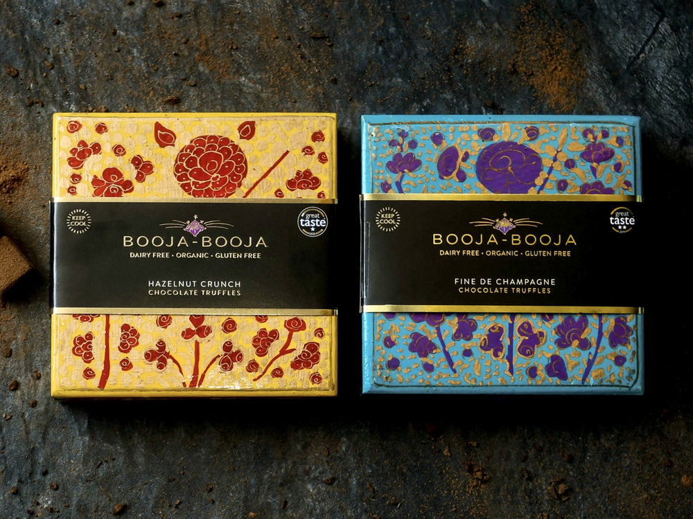 The Booja-Booja Artist's Gift Collection boxes, photographed on a slate background with loose truffles around